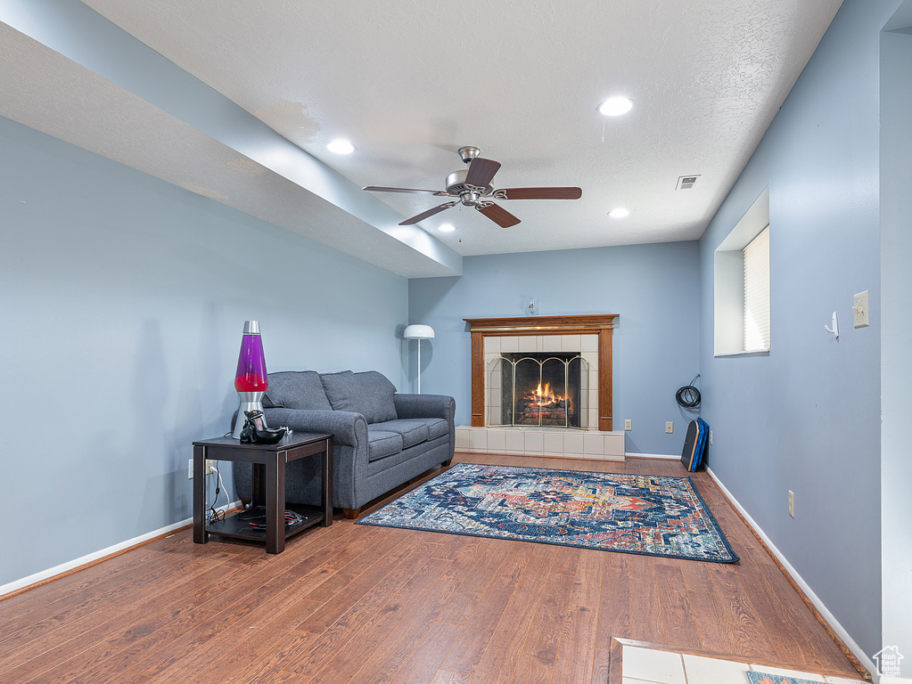 Living area featuring wood finished floors, a ceiling fan, recessed lighting, and a tile fireplace