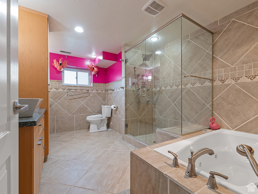 Full bathroom featuring tile walls, a jetted tub, vanity, a stall shower, and tile patterned flooring