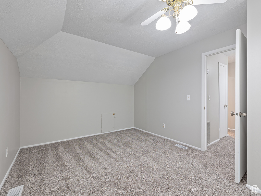 Bonus room with lofted ceiling, carpet flooring, a ceiling fan, and a textured ceiling