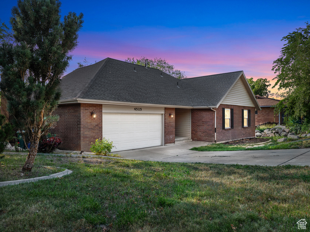 View of front facade with driveway, a garage, brick siding, a front lawn, and roof with shingles