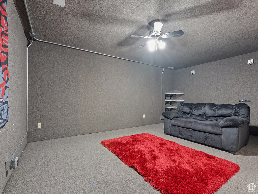 Carpeted living room featuring ceiling fan and a textured ceiling