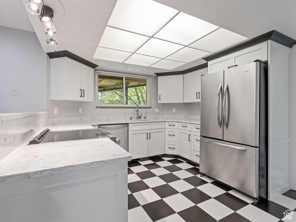 Kitchen with stainless steel appliances, dark floors, and white cabinetry