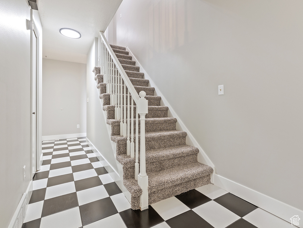 Stairway with tile patterned floors and baseboards