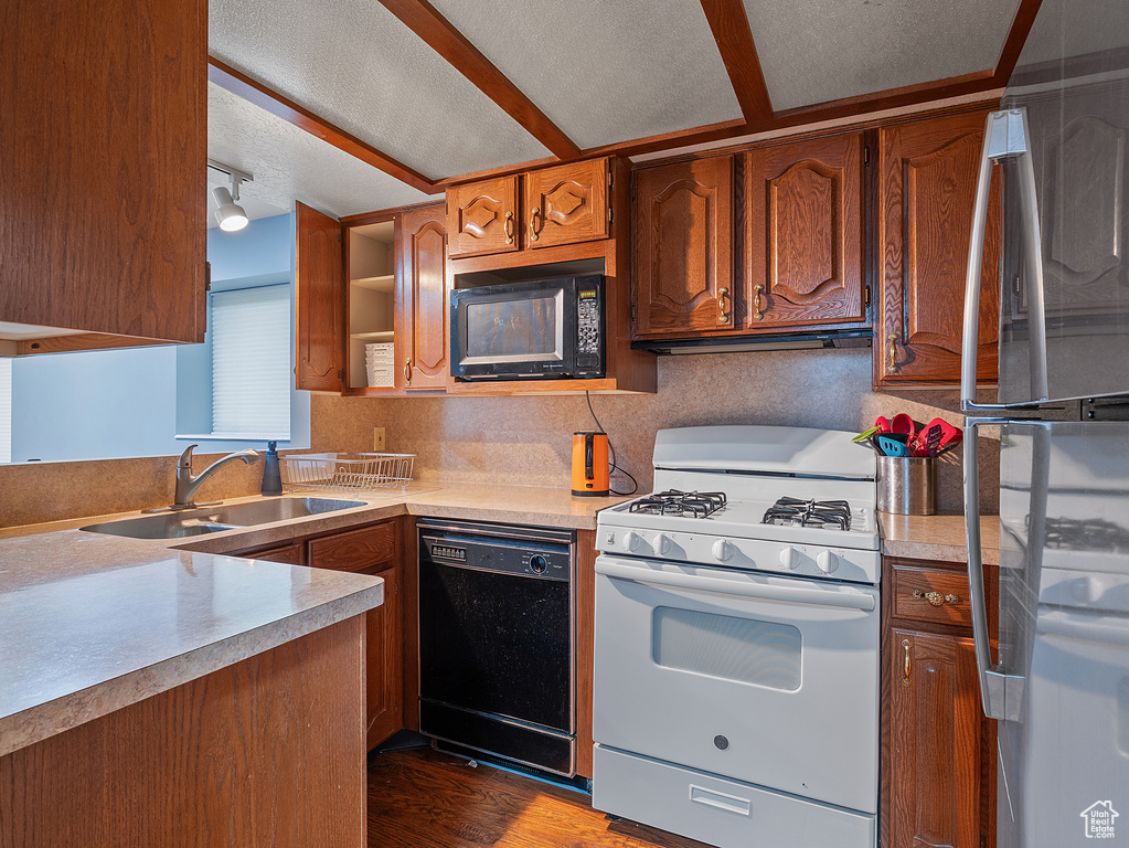 Kitchen featuring black appliances, wood finished floors, light countertops, brown cabinets, and a textured ceiling