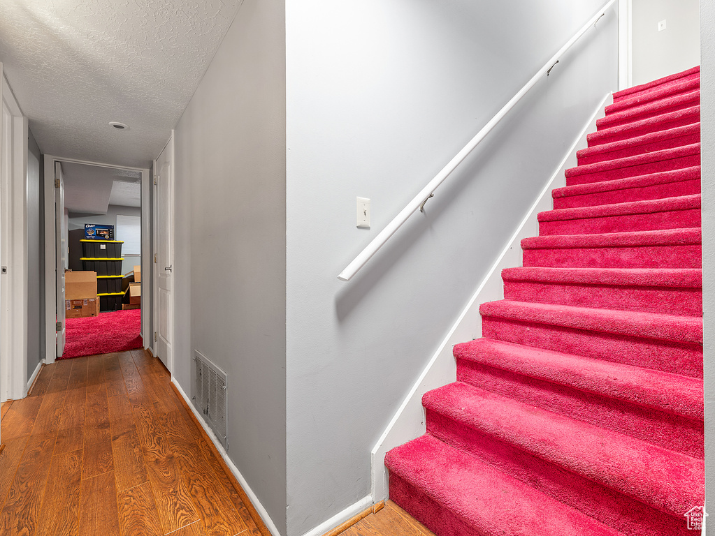 Stairway featuring wood finished floors and a textured ceiling