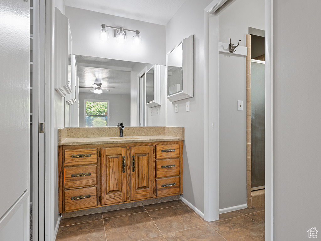 Bathroom with vanity, a ceiling fan, a tile shower, and tile patterned floors
