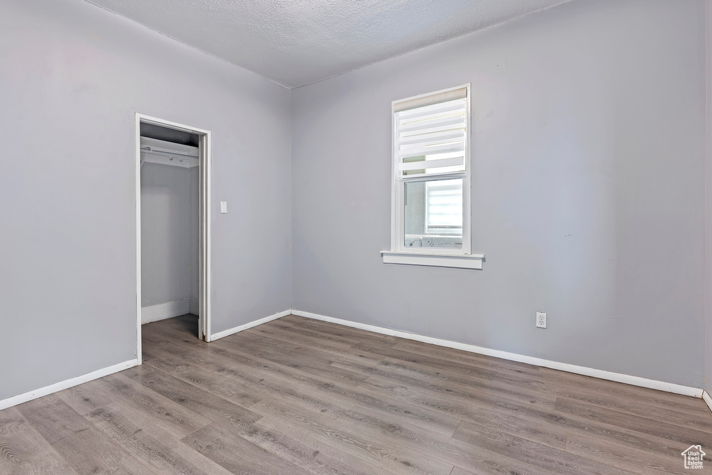 Unfurnished bedroom with wood finished floors, baseboards, and a closet