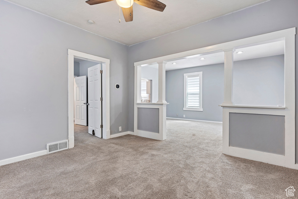 Carpeted empty room with a ceiling fan and baseboards