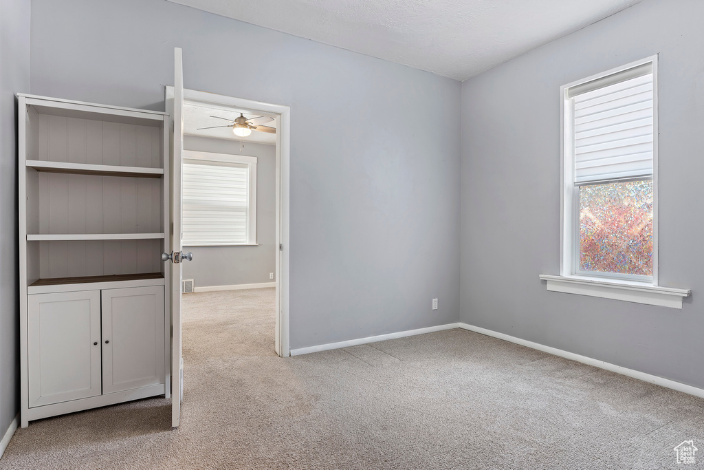 Spare room featuring carpet, a ceiling fan, and baseboards