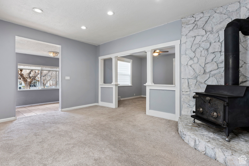 Unfurnished living room featuring carpet floors, a wood stove, baseboards, recessed lighting, and a ceiling fan