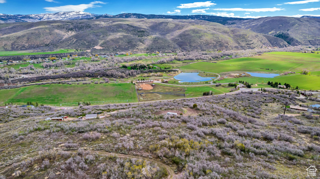 View of mountain backdrop featuring a nearby body of water and a golf course