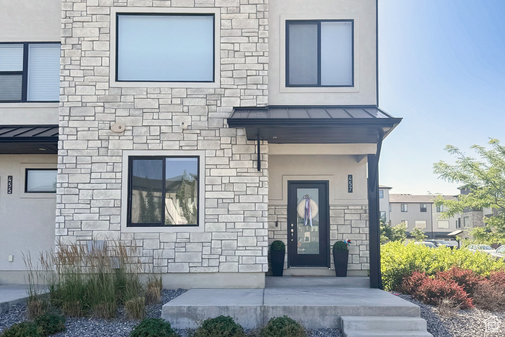 Property entrance with a standing seam roof, stone siding, and a metal roof