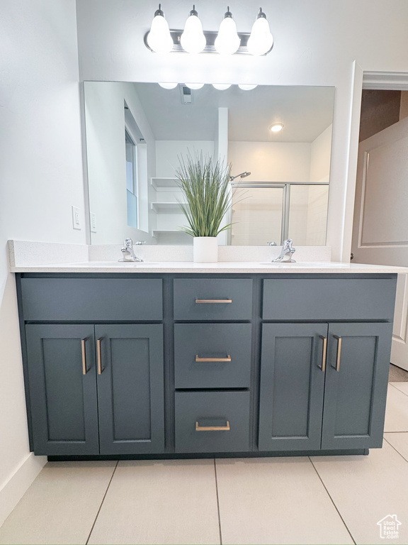 Bathroom with double vanity, tile patterned flooring, and a shower with shower door