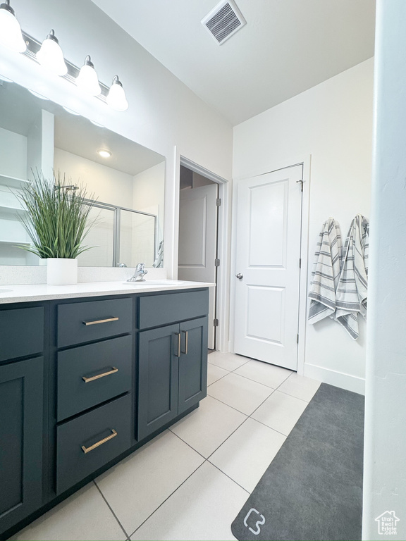 Full bath with double vanity, tile patterned floors, and a shower stall