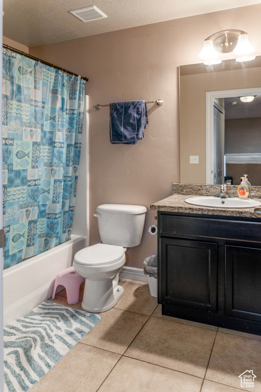 Full bathroom with vanity, tile patterned floors, shower / bathtub combination with curtain, and a textured ceiling