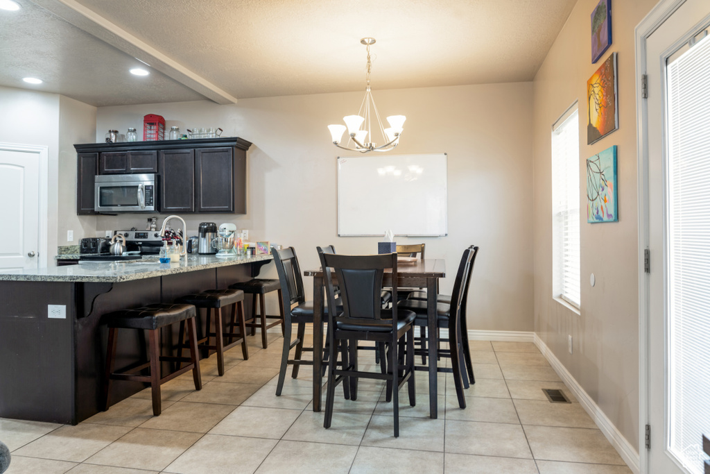 Dining area with a chandelier, light tile patterned floors, and recessed lighting