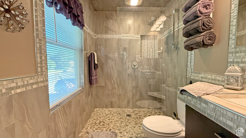 Bathroom with tiled shower, tile walls, and vanity