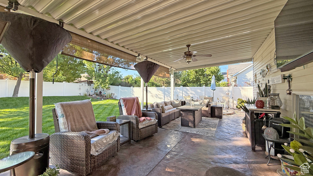 Fenced backyard with outdoor lounge area, a patio, and ceiling fan