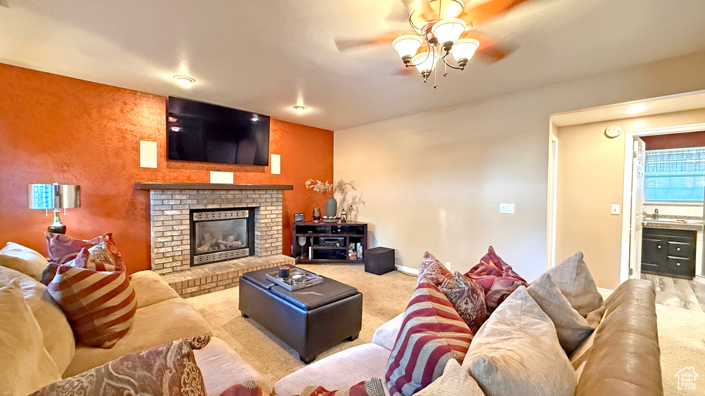 Carpeted living area featuring ceiling fan and a fireplace