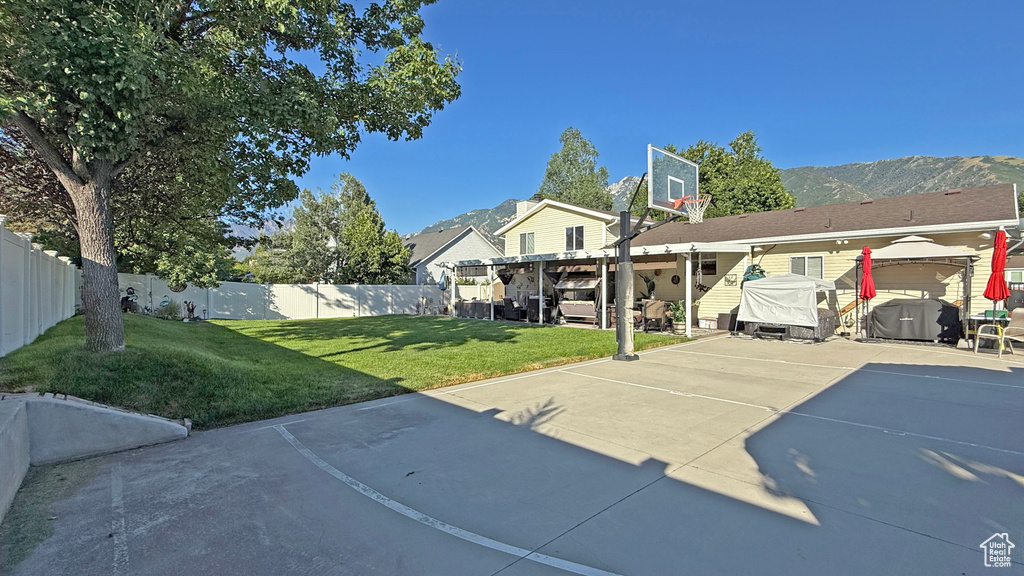 View of basketball court with a fenced backyard and a mountain view