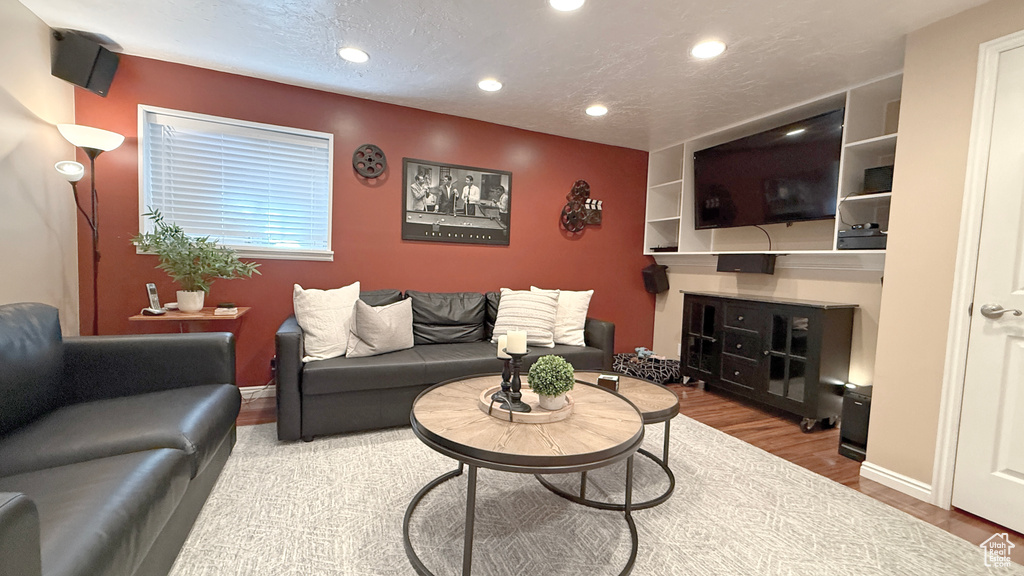 Living room with recessed lighting, wood finished floors, and a textured ceiling
