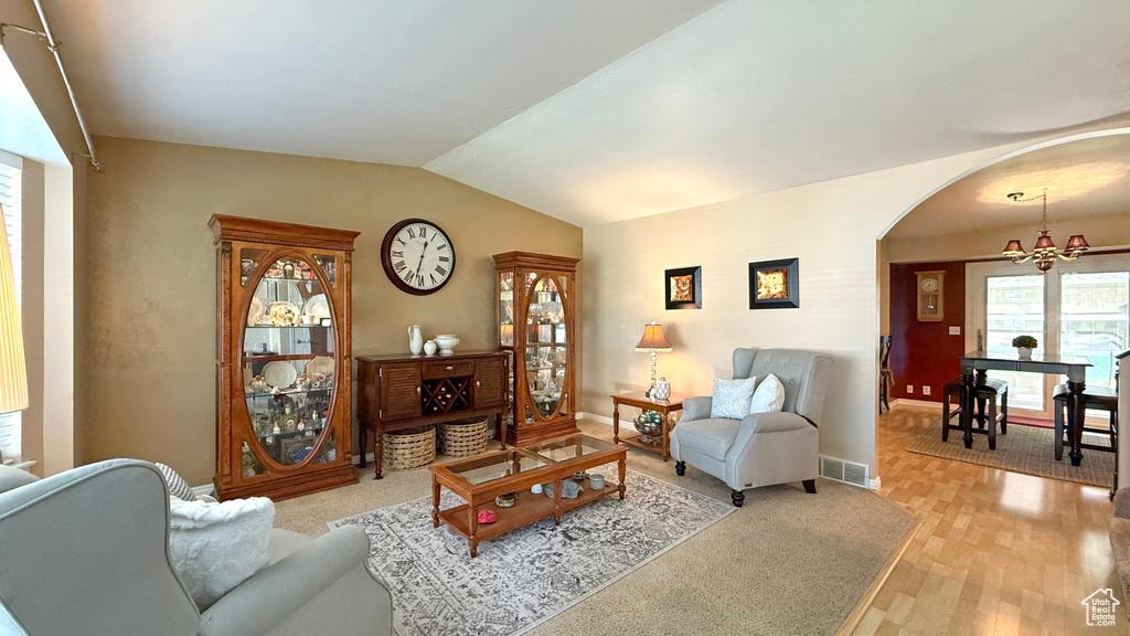 Living room featuring arched walkways, vaulted ceiling, and light wood-style floors
