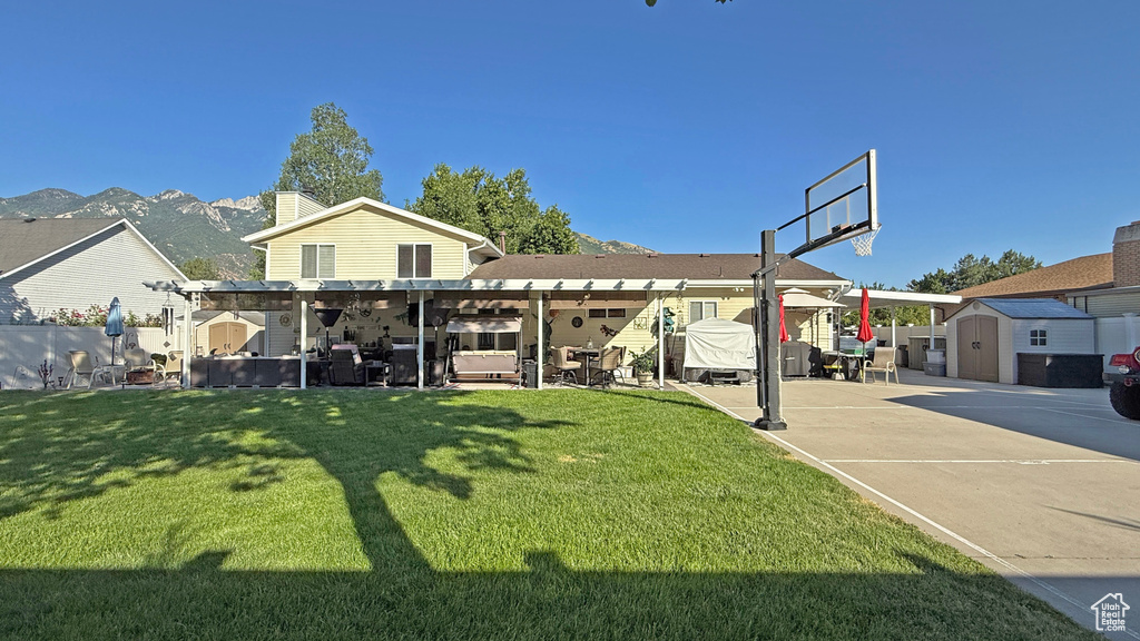Back of property with a storage unit, a pergola, a patio area, a lawn, and a chimney