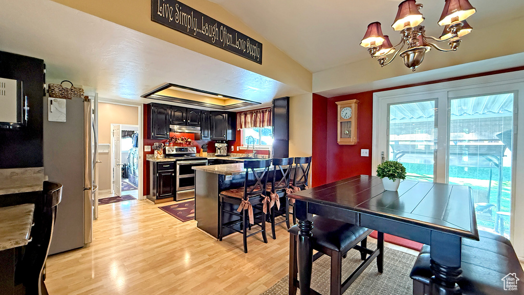 Dining area featuring light wood-type flooring, a chandelier, and lofted ceiling