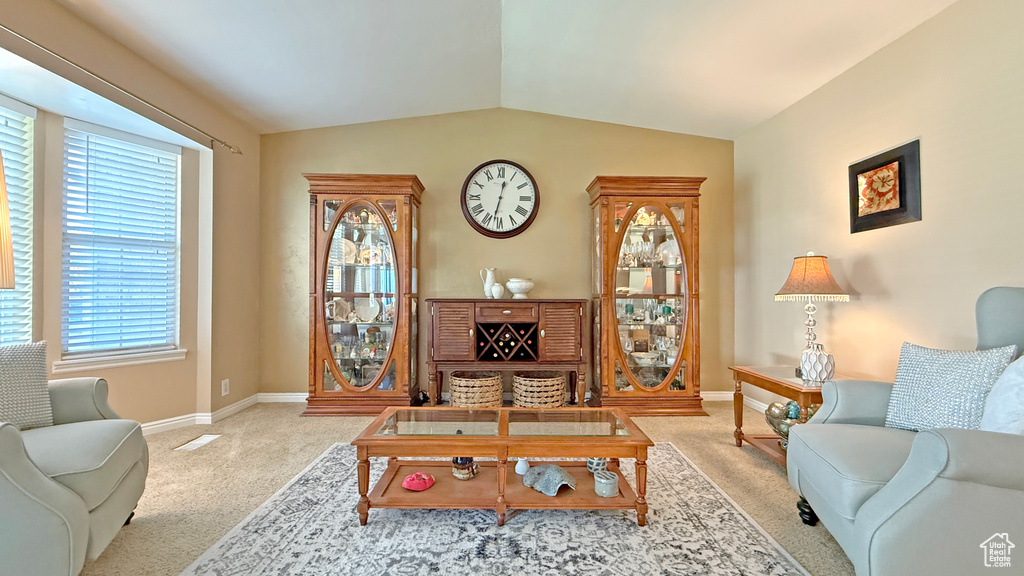 Carpeted living area with vaulted ceiling and baseboards