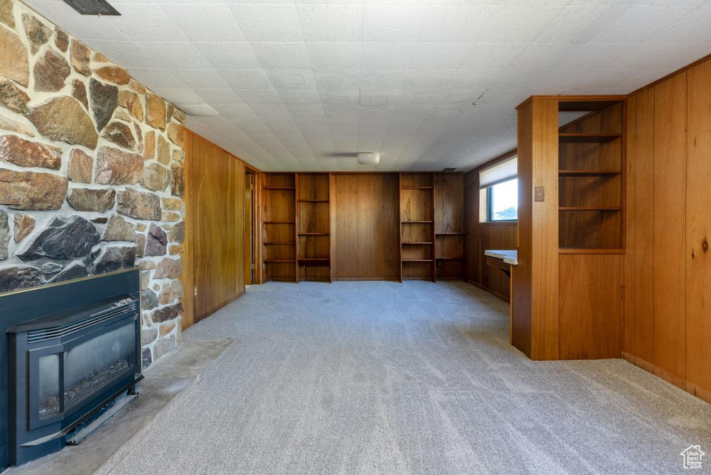 Unfurnished living room with wood walls, carpet, and built in shelves