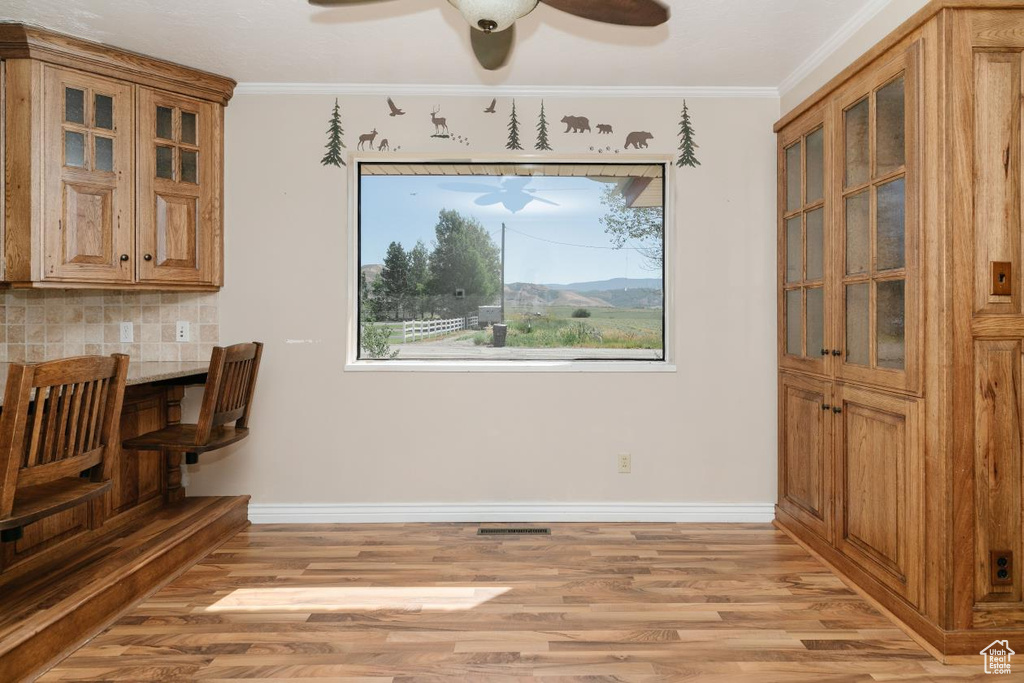 Unfurnished dining area featuring a ceiling fan, light wood finished floors, and ornamental molding