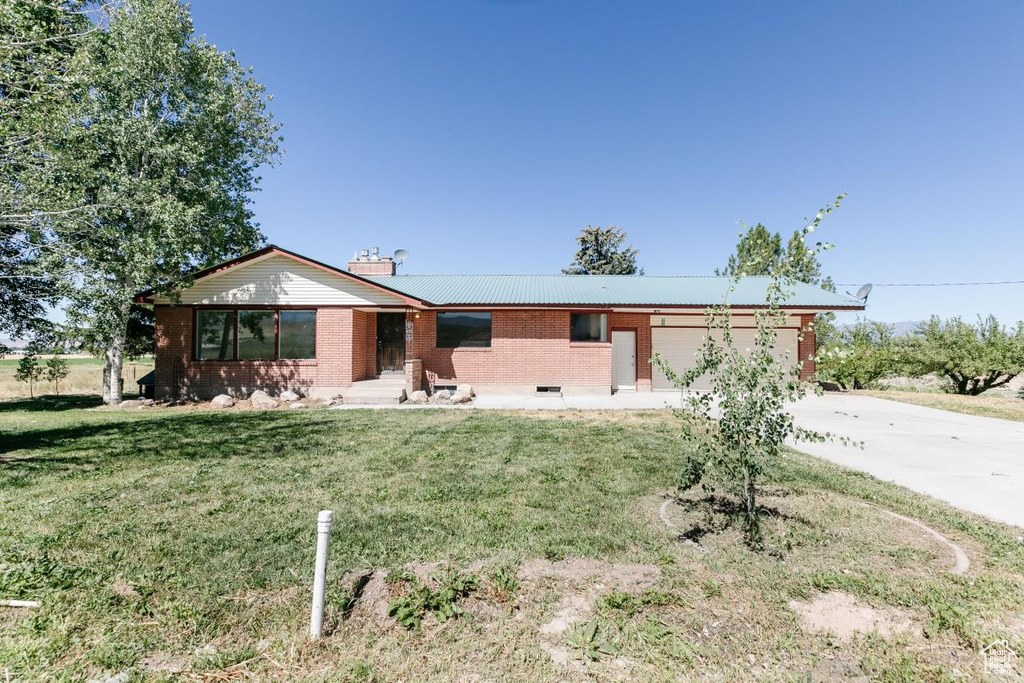 Single story home with concrete driveway, a garage, brick siding, and a front lawn