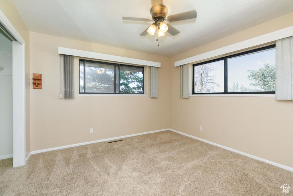 Carpeted spare room with a ceiling fan and baseboards