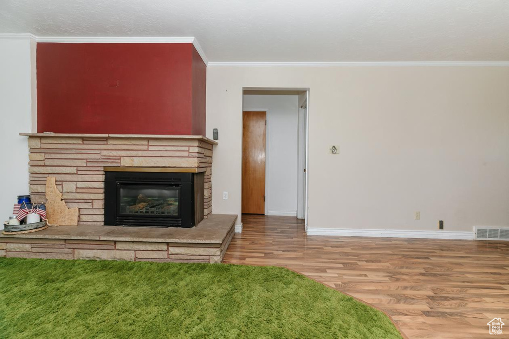 Unfurnished living room with wood finished floors, crown molding, and a fireplace