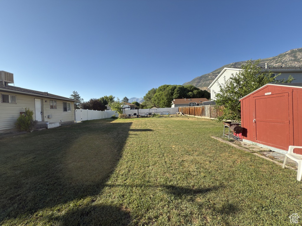 Fenced backyard featuring a storage unit and a mountain view