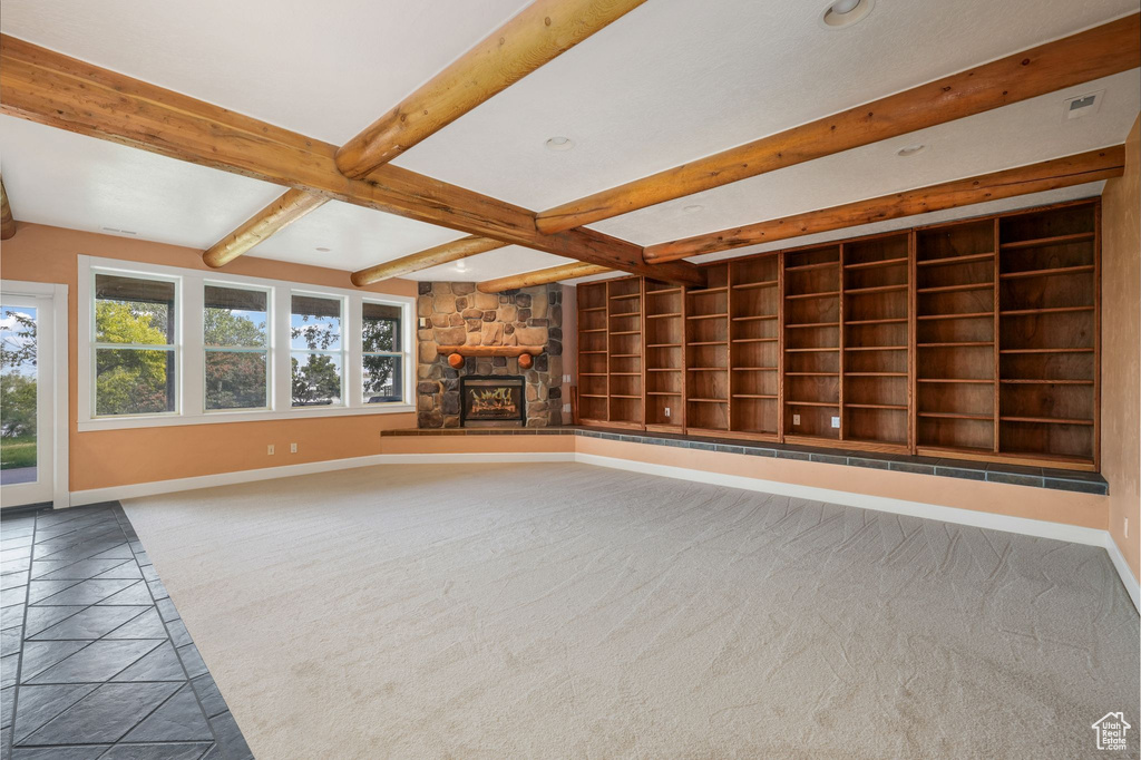 Unfurnished living room with carpet flooring, beam ceiling, a fireplace, built in features, and recessed lighting