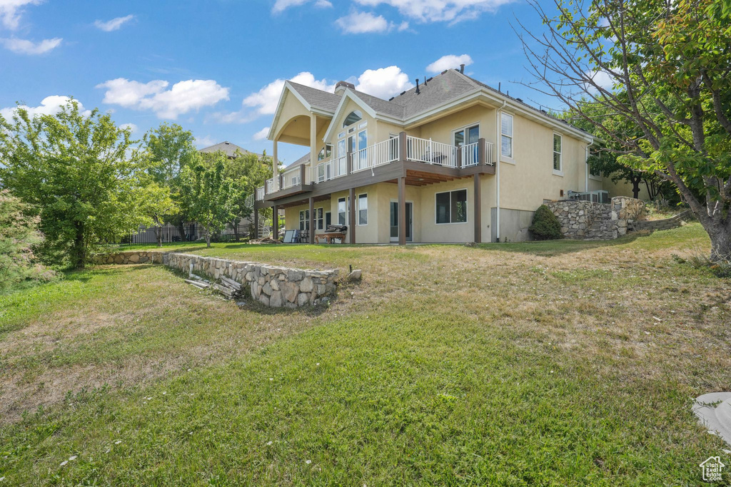 Rear view of property featuring stucco siding and a yard