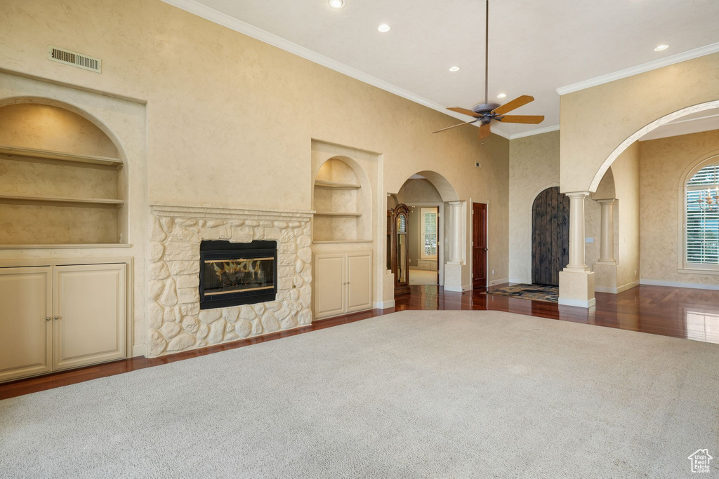 Unfurnished living room with built in shelves, arched walkways, ornate columns, a ceiling fan, and recessed lighting
