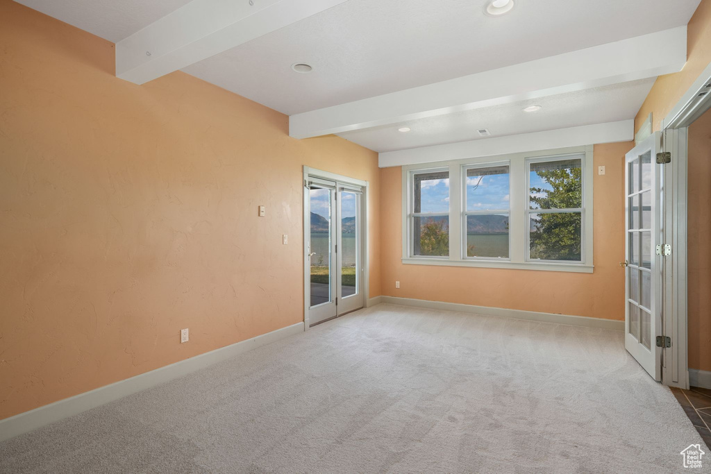 Carpeted empty room with beam ceiling, recessed lighting, and french doors