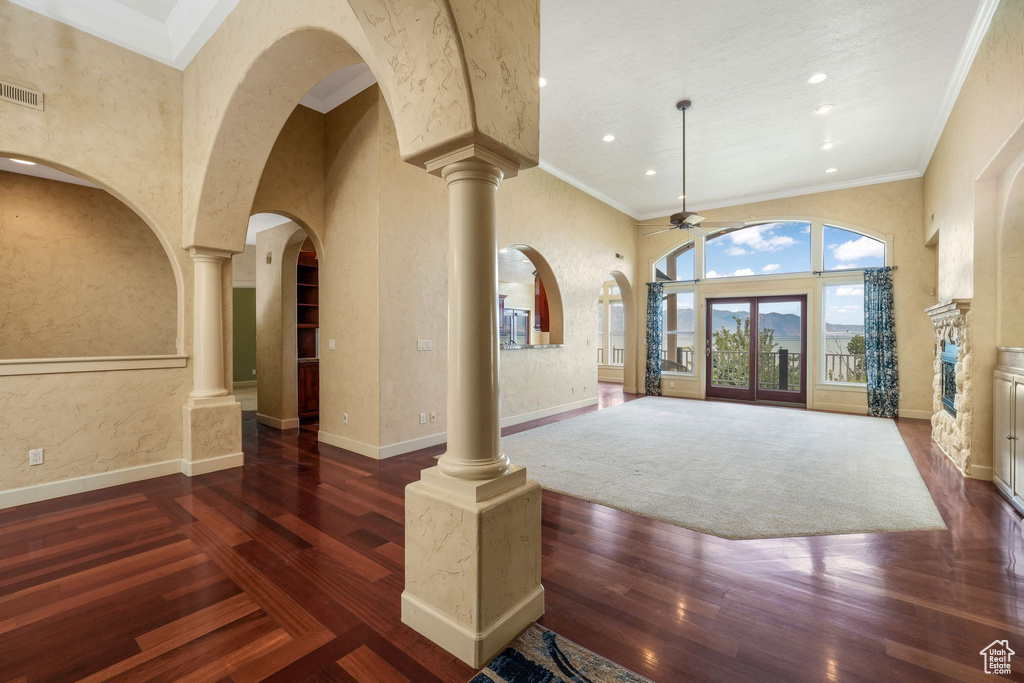 Foyer entrance with ceiling fan, wood finished floors, arched walkways, ornate columns, and a towering ceiling