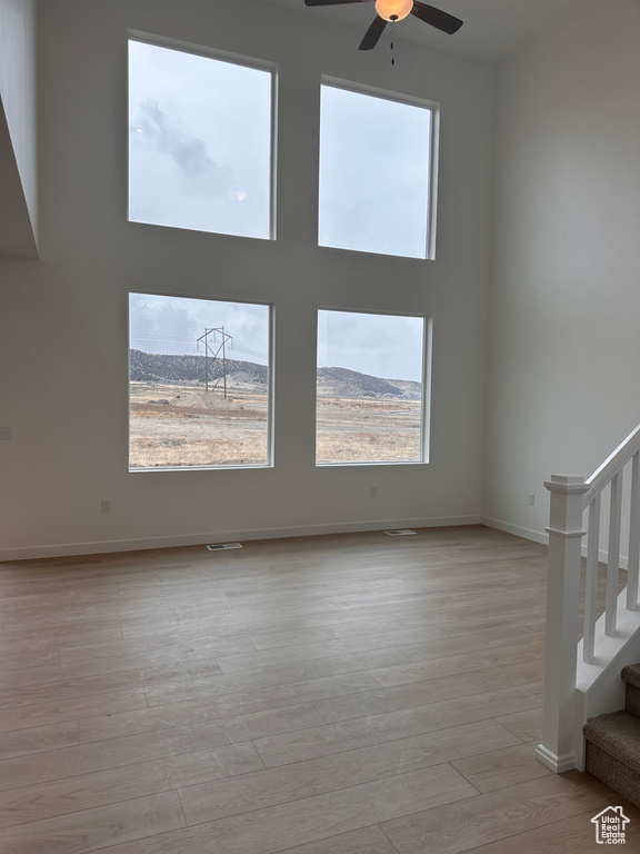 Empty room featuring stairway, a ceiling fan, and wood finished floors