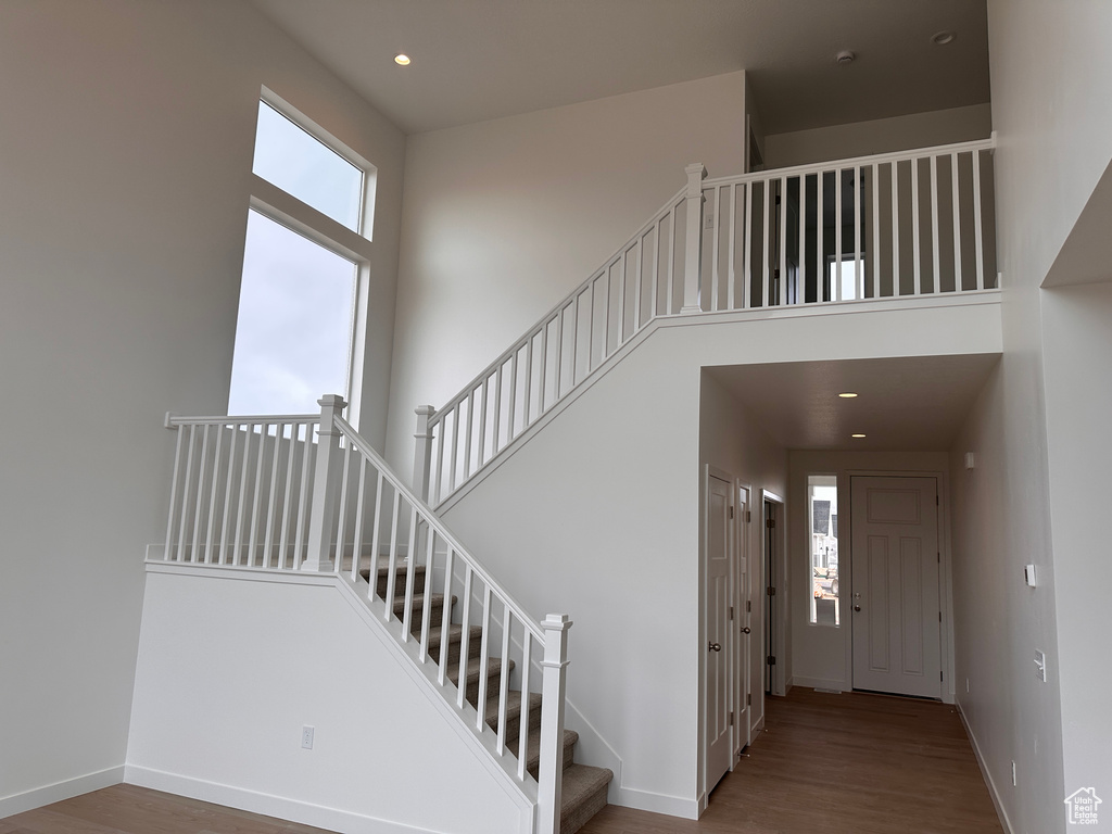 Stairs with wood finished floors, a high ceiling, and recessed lighting