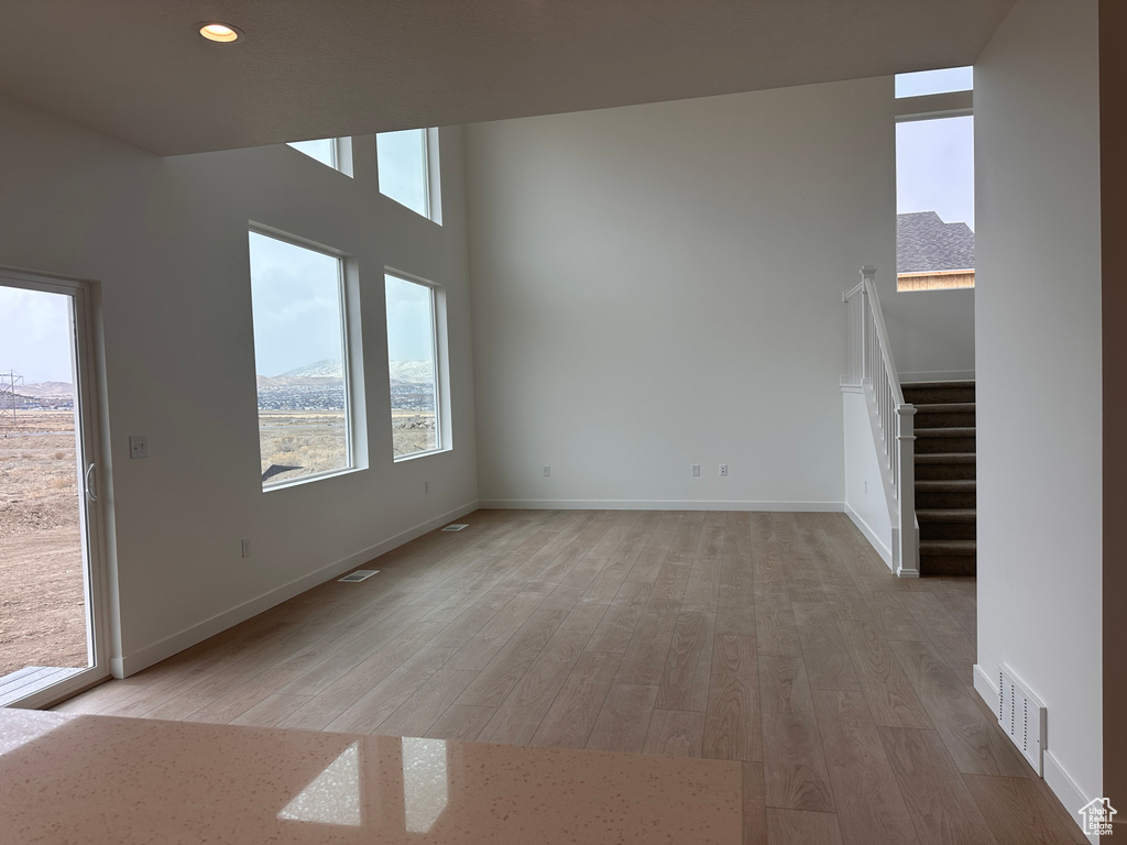 Empty room featuring light wood-style flooring, stairway, and recessed lighting
