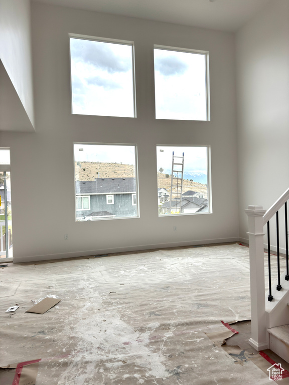 Unfurnished living room featuring stairs and healthy amount of natural light
