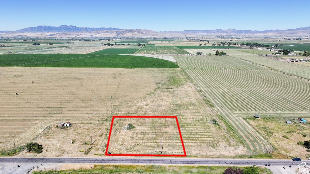 Aerial view of sparsely populated area with farmland, a mountain backdrop, and property boundaries highlighted