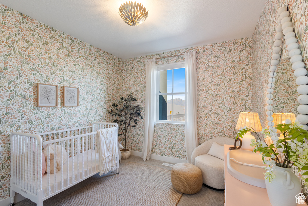Bedroom featuring wallpapered walls and a nursery area