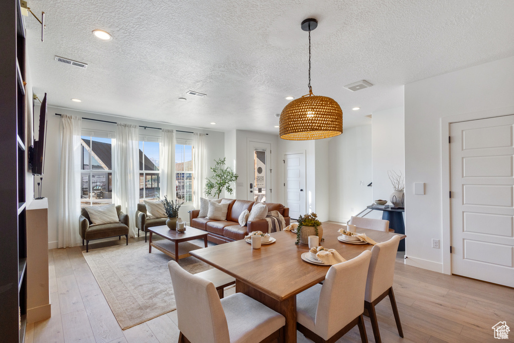 Dining room featuring a textured ceiling, light wood-type flooring, and recessed lighting