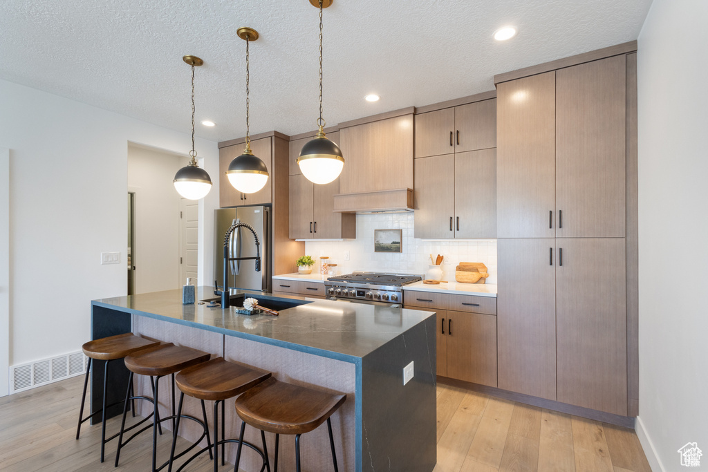 Kitchen featuring stove, a breakfast bar, light wood-type flooring, backsplash, and recessed lighting