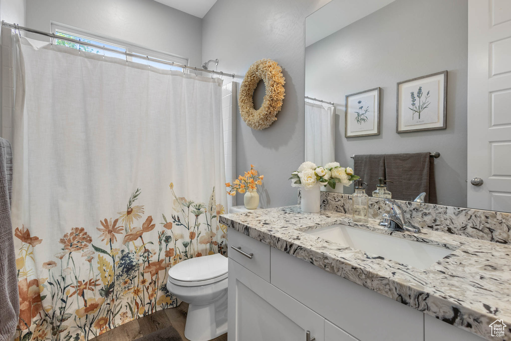 Bathroom with wood finished floors, vanity, and curtained shower