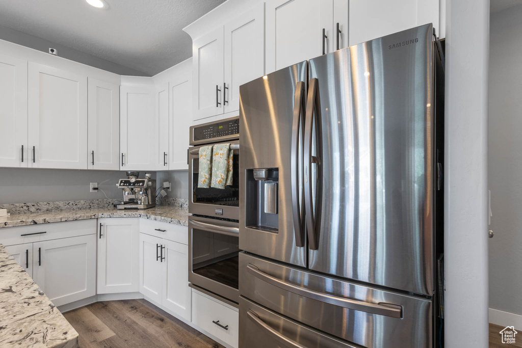 Kitchen featuring appliances with stainless steel finishes, light wood-style floors, white cabinetry, light stone countertops, and recessed lighting